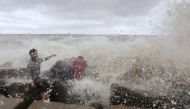 Waves crash into people sitting by the shore of the Bay of Bengal before cyclone Mahasen approaches in Chittagong May 16, 2013. REUTERS/Andrew Biraj