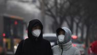 Pedestrians wear masks to protect themselves from pollution in Beijing on December 19, 2016. Hospital visits spiked, roads were closed and flights cancelled on December 19 as China choked under a vast cloud of toxic smog, with forecasters warning worse wa