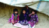 Internally displaced Afghan children sit outside their temporary home at a refugee camp in Kabul yesterday. 