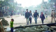 Pedestrians walking past temporary roadblocks on the outskirts of Imphal, yesterday.