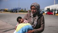 A Syrian asylum seeker holds her baby following their arrival onboard the Eleftherios Venizelos passenger ship at the port of Piraeus, near Athens, Greece September 8, 2015. / Reuters: Alkis Konstantinidis