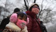 A young girl waits by the road with a relative on a heavily polluted day in Shijiazhuang, in northern China's Hebei province on December 21, 2016. China's smoggiest city closed schools December 21 as much of the country suffered its sixth day under an opp