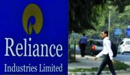 A man walks past a Reliance Industries Limited sign board installed on a road divider in Gandhinagar in Gujarat, India.