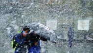 Pedestrians shelter under an umbrella as they walk through heavy snowfall on a road in Shimla, yesterday.