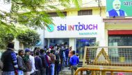 Customers wait in line at a branch of In Touch, operated by State Bank of India Ltd, in Varanasi, Uttar Pradesh.