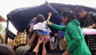Residents are assisted into a truck after the local government implemented preemptive evacuations at Barangay Matnog, Daraga, Albay province on December 25, 2016, due to the approaching typhoon Nock-Ten.  AFP
