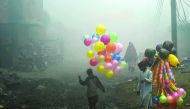 Pakistani balloon vendors cross a street in heavy fog in Lahore on December 24, 2016. / AFP / ARIF ALI