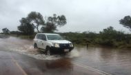 A four-wheel-drive vehicle drives through floodwater caused by heavy rain near the famous Uluru rock formation in central Australia, December 26, 2016. Parks Australia/Handout via REUTERS
