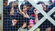 Displaced women, who fled the Islamic State (IS) stronghold of Mosul, stand behind the fence to receive aid at Hassan Sham camp, east of Mosul, Iraq, yesterday.