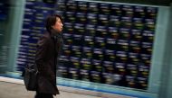 A pedestrian walks past an electronic board displaying stock prices on the Tokyo Stock Exchange in Tokyo on December 26, 2016. AFP / KAZUHIRO NOGI
