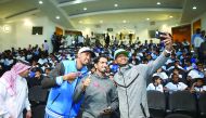 Yasseen Ismail, Mohammed Saadon al Kuwari and Mutaz Barshimtake take a selfie with student-athletes following a panel discussion at the Aspire Academy.