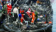 Red Cross and rescue workers on the charred boat, at Muara Angke port in Jakarta, Indonesia, yesterday.