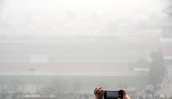 A person takes pictures with a mobile phone of city scenery during a hazy day in Beijing, China, January 1, 2017. Picture taken January 1, 2017. REUTERS/Stringer 