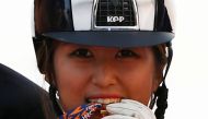 FILE PHOTO: South Korea's Chung Yoo-ra, then known as Chung Yoo-yeon, bites her gold medal as she poses after winning the equestrian Dressage Team competition at the Dream Park Equestrian Venue during the 17th Asian Games in Incheon September 20, 2014. RE