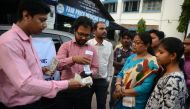 State Bank of India staff assist customers to withdraw money with the use of a mobile banking machine at Siliguri District hospital in Siliguri on November 22, 2016 (AFP / Diptendu DUTTA) 