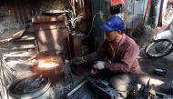 Nguyen Phuong Hung working at his shop on Lo Ren street in downtown Hanoi on December 8, 2016. Sitting before a bright orange flame, he prods a fire pit with a long metal rod before he hammers, bends, and contorts glowing steel into a giant drill bit. Hun