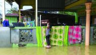 A girl stands on a mailbox outside her house in Malaysia's northeastern town of Rantau Panjang, yesterday.