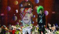 A fan poses in front of the mural of late British pop icon David Bowie on the first anniversary of Bowie's death, yesterday.