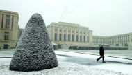 A staff member walks under a snowfall on a winter morning at the European headquarters of the United Nations in Geneva, Switzerland, yesterday.