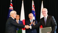 Japan's Prime Minister Shinzo Abe and his Australian counterpart Malcolm Turnbull applaud as Japan's Ambassador to Australia Sumio Kusaka (left) and Australia's Ambassador to Japan Bruce Miller (right) shake hands during a joint signing ceremony at the co