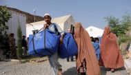 An Afghan family who were living as refugees in Pakistan carries bundles of supplies at a humanitarian aid station in Torkham, Afghanistan, October 22, 2016 (REUTERS / Josh Smith) 
