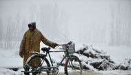 A Kashmiri man rests after riding a bicycle during a snowfall in the outskirts of Srinagar on January 17, 2017. Kashmir has been cut off from the rest of the country after heavy snowfall closing the 294km Jammu-Srinagar national highway, the only road lin