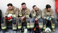 Iranian emergency personnel mourn for lost colleagues and friends as they sit in front of the wreckage of the 15-storey Plasco building which collapsed the previous day, on January 20, 2017, in the capital Tehran. Iranian officials said they were losing h