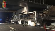 A handout photo provided by the Polizia di Stato on January 21, 2017 shows firefighters standing next to the burnt out wreckage of a bus on a motorway near Verona, after the bus carrying Hungarian teenagers struck a pylon and burst into flames.  AFP / Pol
