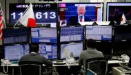 Employees of a foreign exchange trading company work near monitors showing U.S. President Donald Trump (top C) and the Japanese yen's exchange rate against the U.S. dollar in Tokyo, Japan, Jan. 23, 2017. REUTERS/Toru Hanai.