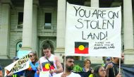 Aboriginal protesters hold signs as they demonstrate outside the Victorian State Parliament on Australia Day, in Melbourne, yesterday.