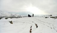 Kashmiri villagers look from the top of a hill on the outskirts of Srinagar after a heavy snowfall, in Srinagar on January 27, 2017. / AFP / Tauseef MUSTAFA