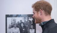 Britain's Prince Harry (R) looks at a photo of his mother, Princess Diana, posing with staff and service users of The Running Charity in northwest London on January 26, 2017 as Prince Harry visits the charity to learn about its activities.  AFP / POOL / G