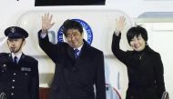 Japan's Prime Minister Shinzo Abe (C) and his wife Akie (R) wave to people seeing them off from the government plane before leaving Haneda Airpot in Tokyo for Washington DC on February 9, 2017. AFP / JIJI PRESS / STR
