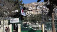 Afghan bystanders gather as The International Committee of the Red Cross (ICRC) flag flies at half-mast at the entrance to the ICRC Orthopaedic Centre in Kabul on February 9, 2017. AFP / SHAH MARAI