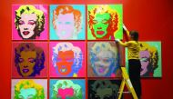 An employee poses with screen prints of Marilyn Monroe by Andy Warhole as part of the exhibition”American Dream: pop to the present” at British Museum in London
