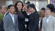 Hollywood star Angelina Jolie (3rd L) and her children including Maddox Jolie-Pitt (C) gesture to media in front of the royal residence for a meeting with Cambodian King Norodom Sihamoni in Siem Reap on February 18, 2017.AFP / TANG CHHIN SOTHY
