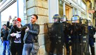 Young men (L) take provocative selfie photos as anti-riot police officers stand guard during a demonstration against police brutality on February 18, 2017 in Rennes, following the alleged rape in the Paris suburb of Aulnay-sous-Bois of a black youth, iden