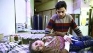 A wounded Syrian girl cries as she waits to receive treatment at a make-shift hospital following an airstrike on the rebel-held town of Douma, yesterday.