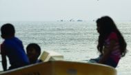 Sri Lankan children look on as navy boats search the waters off Katukurunda along the coast of Sri Lanka yesterday.