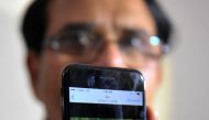 Indian man Jagan Mohan Reddy holds a smartphone with an image of his son Alok Madasani at his residence in Hyderabad on February 24, 2017, after Alok was injured in a shooting in the US state of Kansas. Alok and his friend Srinivas Kuchibhotla were in a b