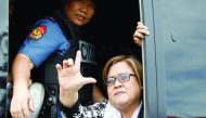 A policewoman guards Philippine Senator Leila De Lima as she gestures a sign that means 