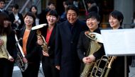 Japan's Prime Minister Shinzo Abe poses with musicians at a concert for Premium Friday, outside a museum in Tokyo, yesterday.