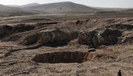 A member of the Hashed al-Shaabi (Popular Mobilisation) paramilitaries, walks next to a sinkhole, known as the Khasfah (an Arabic word for a crack or a hole that opens up in the ground), in the village of Athbah, south of Mosul on February 26, 2017. / AFP