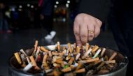 A man grinds out his cigarette in an ashtray at a Shanghai railway station on Feb 28, 2017.PHOTO: AFP.