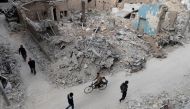 Syrians walk past the rubble of destroyed buildings in the rebel-held town of Douma, on the eastern outskirts of the capital Damascus, on February 27, 2017.  AFP / Abd Doumany