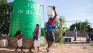 A woman and her children carrying water cans fetched from a tank installed at a church in Luveve on the outskirts of Bulawayo on November 24, 2016 (AFP / Zinyange Auntony)  