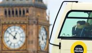 A woman riding on the top deck of a tour bus points out as she passes the Elizabeth Tower, also known as Big Ben at the Houses of Parliament in central London on March 1, 2017. The House of Lords looks set today to defy Prime Minister Theresa May by deman
