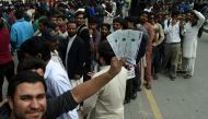 A Pakistani cricket fan poses showing his tickets of the forthcoming Pakistan Super League (PSL) final cricket match as others stand in a queue outside a bank in Lahore. (AFP / ARIF ALI)