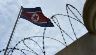 The North Korean flag is seen past a barbed-wire fenced wall of the North Korean embassy in Kuala Lumpur on March 5, 2017. AFP / Lillian Suwanrumpha 