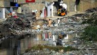 In this photograph taken on January 24, 2017, Pakistani youths search for their ball as they walk amongst dumped garbage at a residential area of Karachi. AFP / Rizwan Tabassum 